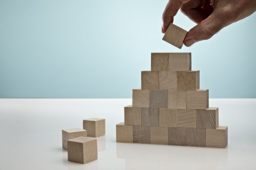 Blocks stacked into a pyramid on Blue Background - ponzi scheme concept