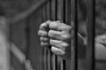 hands gripping the bars of a jail cell - federal criminal penalties concept