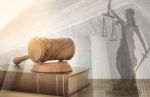 Judge gavel on law books with statue of justice and court building - federal criminal process concept